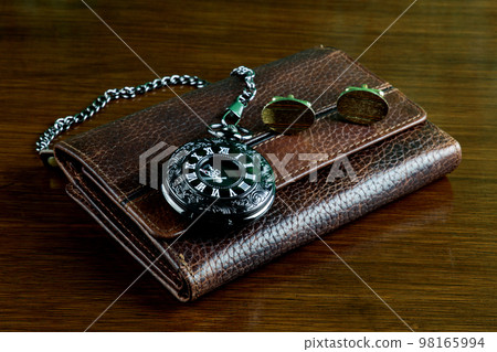 Black Pocket Watch with Leather Wallet and Gold Cuff Links on a Wooden Table Top Black Pocket Watch with Leather Wallet and Gold Cuff Links on a Wooden Table Top 98165994