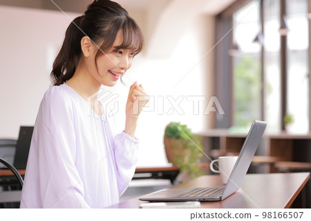 A young woman who completes the document creation and makes a guts pose with her left hand_3 98166507