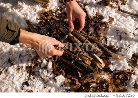 close-up male hands starting a fire in forest. Lighting a fire in nature, forest by male person. 98167250