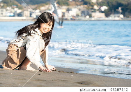 冬天在沙灘上玩耍的年輕少女 冬天在沙灘上玩耍的年輕少女 98167342