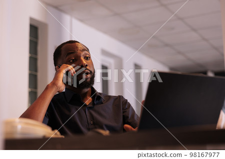 Financial analyst discussing company report with colleague on smartphone, african american man answering teamlead mobile call. Corporate worker having telephone conversation in coworking space Financial analyst discussing company report with colleague on smartphone, african american man answering teamlead mobile call. Corporate worker having telephone conversation in coworking space 98167977