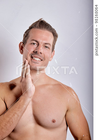 Happy smiling macho man guy holding hands touch perfect skin on face, posing Happy smiling macho man guy holding hands touch perfect skin on face, posing 98168064