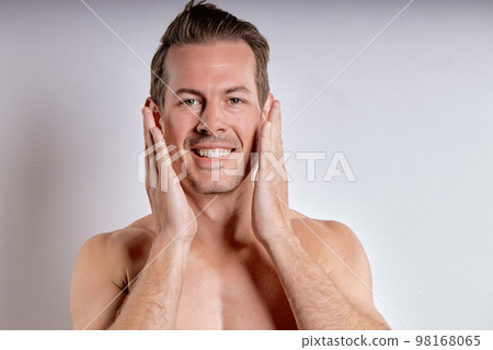Close-up portrait of happy caucasian guy with wet sexy body posing, touching face 98168065