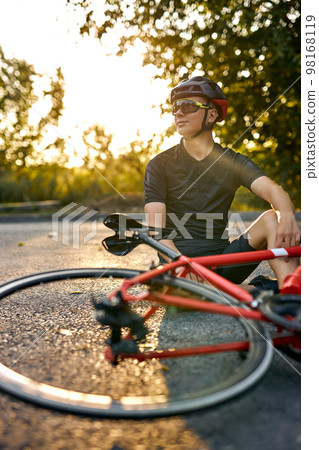 young Biker man resting during riding the bike in nature countryside, sit on road. young Biker man resting during riding the bike in nature countryside, sit on road. 98168119