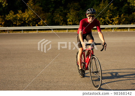 sportive male bicyclist riding bike and observing environment in countryside road sportive male bicyclist riding bike and observing environment in countryside road 98168142