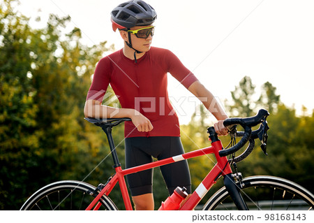 fit male cyclist wearing professional sportswear standing near bicycle on road 98168143