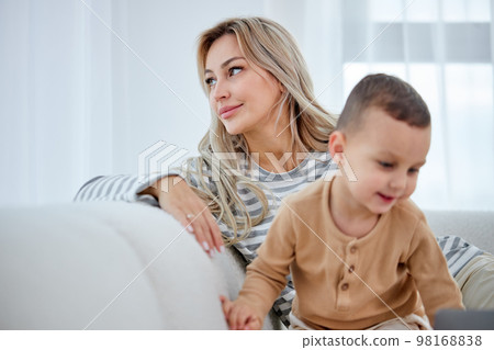 adorable cute child boy watching cartoons, spending time with mom at home adorable cute child boy watching cartoons, spending time with mom at home 98168838
