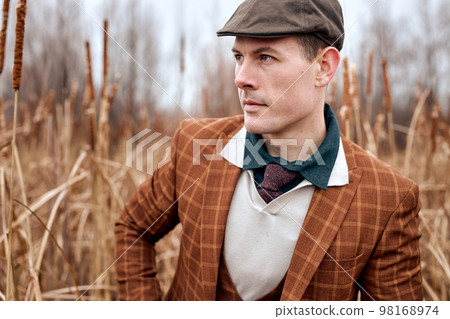 hunter man in trendy suit stands in nature looks out for game, on autumn season 98168974