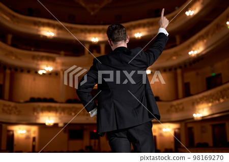 back view on man in suit talking giving motivation training from speaker stage back view on man in suit talking giving motivation training from speaker stage 98169270