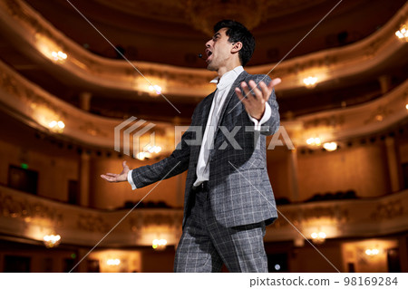 talented singer in elegant classic outfit, singing hit with open mouth in microphone talented singer in elegant classic outfit, singing hit with open mouth in microphone 98169284