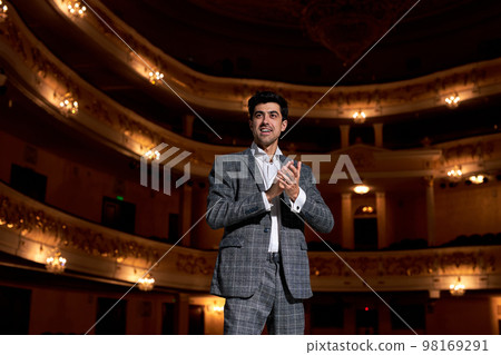 Young business couch standing on stage clapping hands, keep hands together 98169291