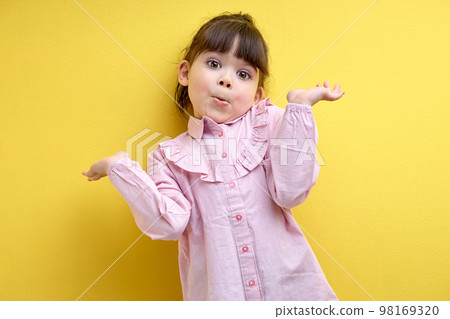 misunderstanding child girl shrugging, i don't know concept. isolated yellow background 98169320