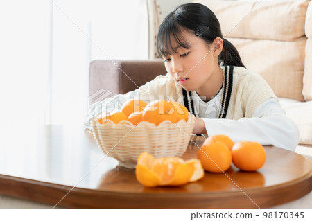 Asian woman eating oranges on the kotatsu in the living room 98170345