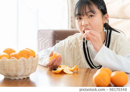 Asian woman eating oranges on the kotatsu in the living room Asian woman eating oranges on the kotatsu in the living room 98170348