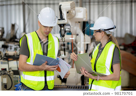 Engineer man and woman talking and explaining about robot arms technology intelligence. Engineer man and woman talking and explaining about robot arms technology intelligence. 98170701