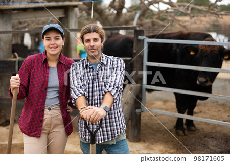 Portrait of happy family couple of farmers in backyard of farm 98171605