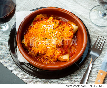 Cannelloni with minced meat and cheese in earthenware dish 98171662