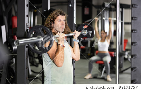 Caucasian man doing exercises usining barbell and half rack in gym 98171757