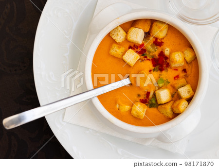 Spanish cold soup gazpacho in bowl with tomatoes, cucumber, baked breads and onion 98171870