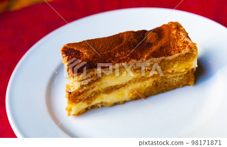 Slice of fresh tiramisu cake on white plate Slice of fresh tiramisu cake on white plate 98171871