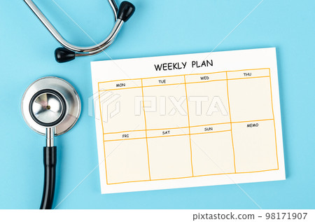 The Blank weekly plan notice block and medical stethoscope on blue colour background. 98171907