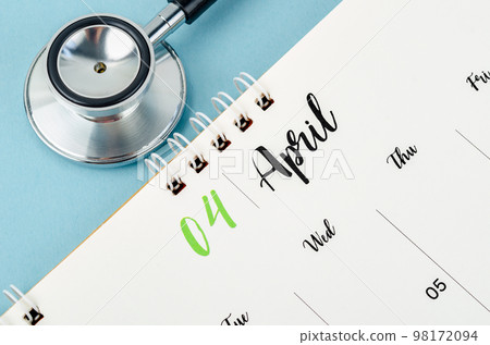 A April 2023 deskcalendar and medical stethoscope medical on blue background. 98172094