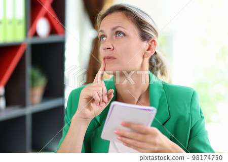 Female manager thinking with notebook and pen in hands. 98174750