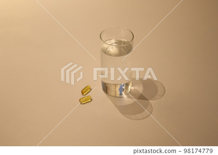 Pills and water cup lying on a white table 98174779