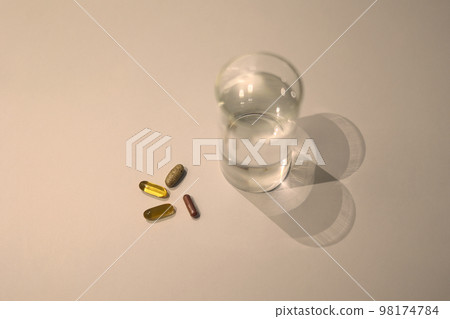Various medicines and water cups placed on a white table Various medicines and water cups placed on a white table 98174784