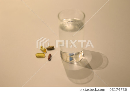 Various medicines and water cups placed on a white table 98174786