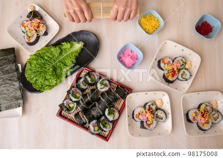 Hands of a woman who enjoys hand-rolled sushi 98175008