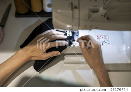 Hands of a woman stitching fabric with a sewing machine Hands of a woman stitching fabric with a sewing machine 98176724