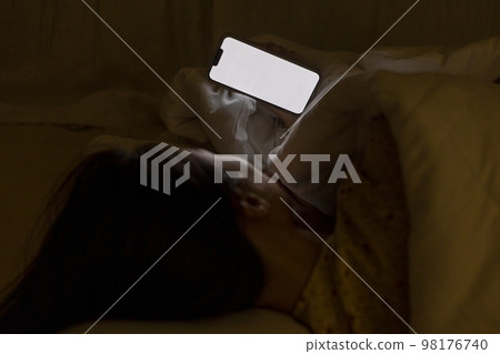 一個女人躺在床上,蓋著毯子,看著手機的後視圖 一個女人躺在床上,蓋著毯子,看著手機的後視圖 98176740