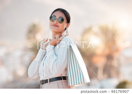Retail shopping bag, urban woman and portrait travel for discount sales, market and outdoor sun in Dubai. Happy rich arab customer, consumer and wealthy person with sunglasses buying luxury fashion 98176907