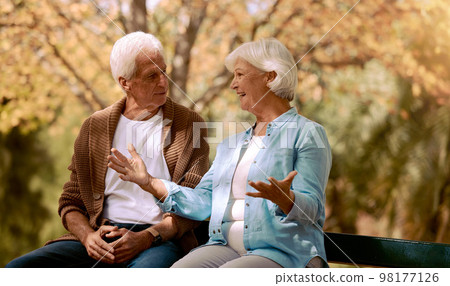 Nature, park and retirement with a senior couple sitting together on a wooden bench outdoor in a garden. Spring, love and summer with a mature man and woman bonding outside in the countryside 98177126