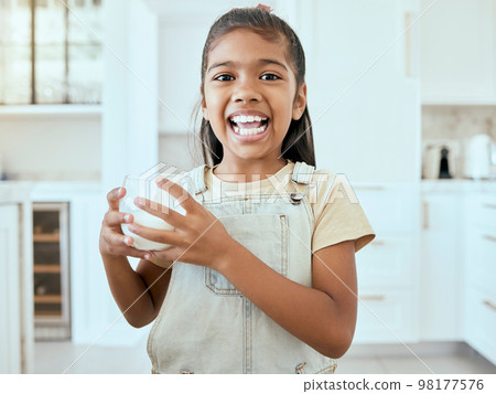 Milk, portrait and child with a healthy drink for energy, growth and nutrition in the kitchen of a house. Happy, young and girl with a smile for calcium in a glass for breakfast and care for teeth 98177576