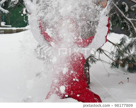 A teenager plays with snow in the forest on a sunny winter day.Healthy lifestyle.Winter fun.Blurred image and flying snow. A teenager plays with snow in the forest on a sunny winter day.Healthy lifestyle.Winter fun.Blurred image and flying snow. 98177809
