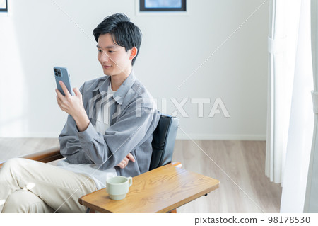 A young man looking at his smartphone 98178530