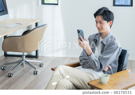 A young man looking at his smartphone 98178531