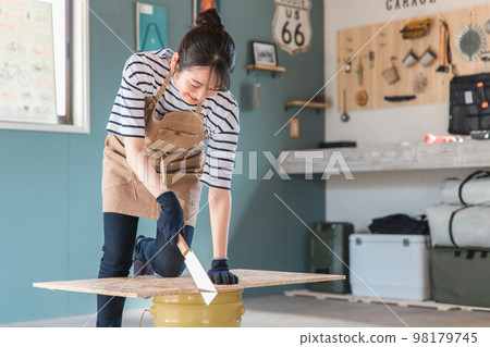 亞洲女人在她家的車庫裡用鋸子鋸木頭（DIY 班、工作坊、DIY、體驗班） 98179745