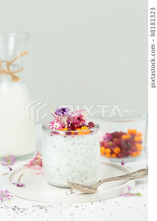 Pudding with chia seeds and edible flowers. Close-up, on a light background, vertical 98181323