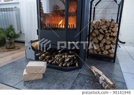 Fuel briquettes made of pressed sawdust for kindling the furnace - economical alternative eco-friendly fuel for the fireplace in the house. Firewood is burning in the oven in the interior 98181946