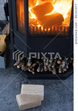 Fuel briquettes made of pressed sawdust for kindling the furnace - economical alternative eco-friendly fuel for the fireplace in the house. Firewood is burning in the oven in the interior 98181977