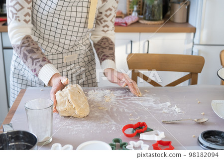 Hands knead thick dough on the kitchen table, decorated with festive decorations for Christmas and New year. Baking at home, aroma and comfort. Close-up Hands knead thick dough on the kitchen table, decorated with festive decorations for Christmas and New year. Baking at home, aroma and comfort. Close-up 98182094