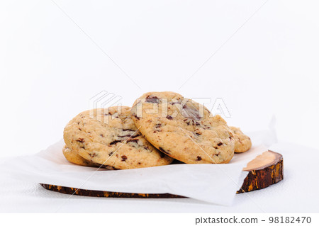 Homemade stacked chocolate chip cookies on wooden plate and white background 98182470
