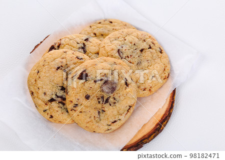 Homemade stacked chocolate chip cookies on wooden plate and white background 98182471