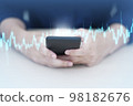 Trader using mobile phone app analytics for cryptocurrency graph. 98182676