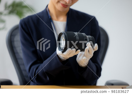 Woman assessing a camera lens Woman assessing a camera lens 98183627