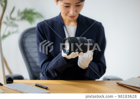 Woman assessing a camera lens 98183628