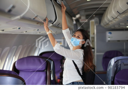 Traveling and Business during COVID-19 virus pandemic concept,woman wearing protective mask sitting near windows on airplane during flight 98183794